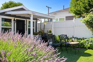 A covered patio area with a white fence, outdoor seating, and a row of lavender plants. - Chestnut Cottage- Cozy Cottage for Two! (Paso Robles)