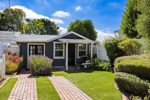 A single-story house with a small front porch, a paved driveway, and a well-maintained lawn. - Chestnut Cottage- Cozy Cottage for Two! (Paso Robles)