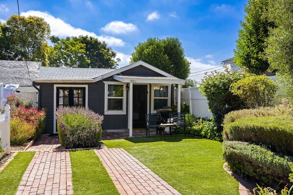 A single-story house with a small front porch, a paved driveway, and a well-maintained lawn. - Chestnut Cottage- Cozy Cottage for Two! (Paso Robles)