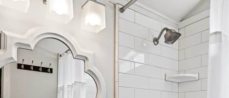 Une salle de bain avec un lavabo blanc, un miroir et une douche.