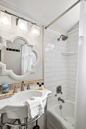 Een badkamer met een wit wastafelmeubel, spiegel en douche.