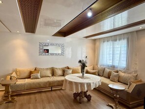 Ein Wohnzimmer mit einem beigen Sofa, einem runden Couchtisch und einem dekorativen Spiegel an der Wand.