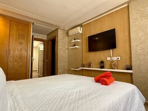 A hotel room with a bed, a television mounted on the wall, and a wardrobe. - Theatro Kénitra Apartment (Kénitra)