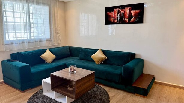 Una sala de estar moderna con un sofá modular color turquesa, una mesa de centro de madera y un cuadro grande en la pared.