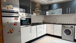 Una cocina moderna con electrodomésticos de acero inoxidable, salpicadero decorativo y lavadora integrada.