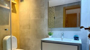 Un baño moderno con inodoro, lavamanos y espejo.