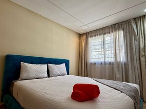 Ein Hotelzimmer mit einem Bett, einem Fenster mit Vorhängen und einer Decke mit Einbuchtungslampen.