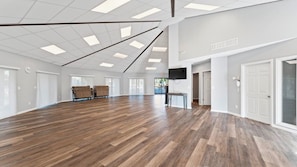 A spacious room with a wooden floor, white walls, and a ceiling with recessed lighting. - Coastal St. Augustine Beach Condo | Partial Ocean View | Resort Amenities | Steps to the Beach | Sleeps 6 (St. Augustine)