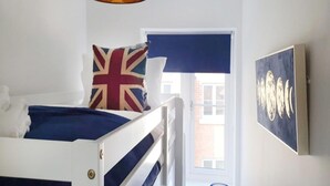 A bedroom with a bunk bed, a flag pillow, a painting, and a window with a view. - Holiday Home Near Centre of Whitby (Whitby)