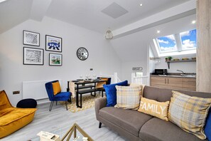 Ein stilvolles Wohnzimmer mit einer Couch, Sesseln, einem Esstisch und Kunstwerken an den Wänden.
