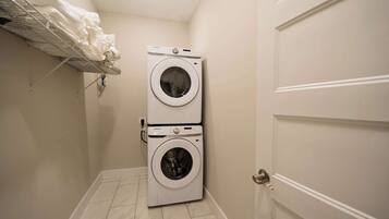 A compact laundry room with two stacked washing machines and a drying rack.