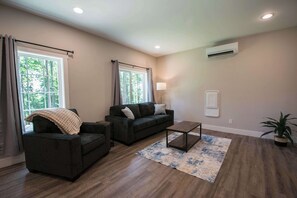A living room with a sofa, armchair, coffee table, and a potted plant. - Druid Hills Retreat II | Sleeps 8 | Free Tix (Hendersonville)