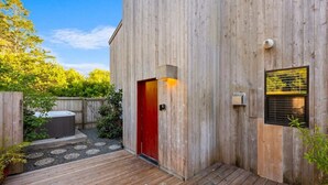 A wooden building with a red door, a small window with blinds, and a wooden deck. - 2BR w/Ocean View & Hot Tub, Near Black Point Beach (Sea Ranch)