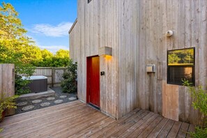 A wooden building with a red door, a small window with blinds, and a wooden deck. - 2BR w/Ocean View & Hot Tub, Near Black Point Beach (Sea Ranch)