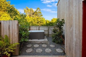 Ein Garten mit Whirlpool, Holzzaun und Kiesweg.