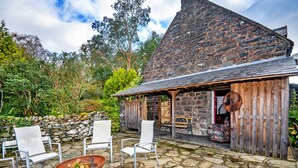 A stone building with a covered patio area, stone walls, and a fire pit. - Scenic Dales Hut With Hot Tub for 2 (Dolgellau)