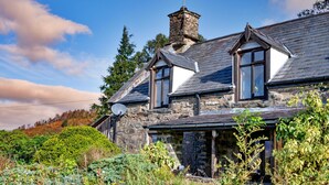 A stone house with a steeply pitched roof, multiple chimneys, and a satellite dish. - Scenic Dales Hut With Hot Tub for 2 (Dolgellau)