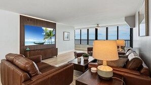 A modern living room with a large window, leather sofas, a coffee table, and a view of the sea. - Punta Rassa Luxe Waterfront w/ Panoramic Views, Gorgeous Sunsets, Pool, Hot Tub (Fort Myers)