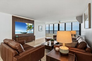 Ein modernes Wohnzimmer mit großem Fenster, Ledersofas, einem Couchtisch und Meerblick.