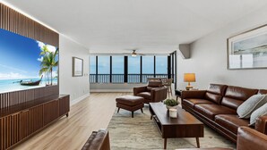 A modern living room with a view of the sea, a ceiling fan, and a large window. - Punta Rassa Luxe Waterfront w/ Panoramic Views, Gorgeous Sunsets, Pool, Hot Tub (Fort Myers)