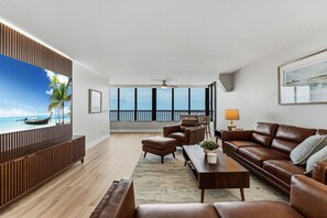 Ein modernes Wohnzimmer mit Meerblick, einem Deckenventilator und einem großen Fenster.