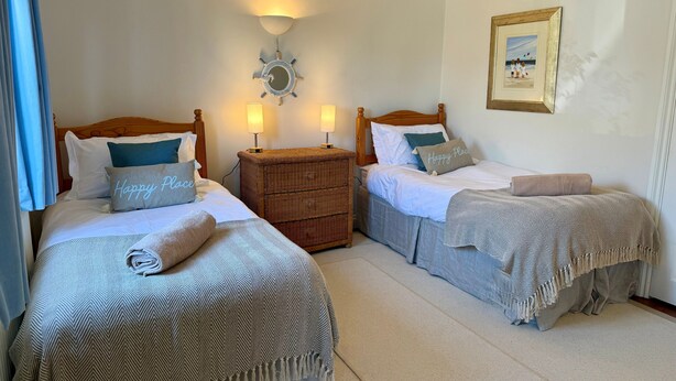 Quarto de hotel com duas camas, uma cômoda, um espelho fixado na parede e um quadro emoldurado.