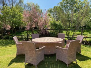 A round wooden table with wicker chairs in a garden setting. - Caldarvan - sleeps 8 guests  in 4 bedrooms (Wadebridge)