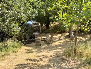 A secluded outdoor seating area with a transparent gazebo, surrounded by dense foliage and a rustic vase. - Caldarvan - sleeps 8 guests  in 4 bedrooms (Wadebridge)
