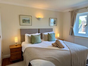 A neatly made bed with pillows, a bedside lamp, and a framed picture on the wall. - Caldarvan - sleeps 8 guests  in 4 bedrooms (Wadebridge)