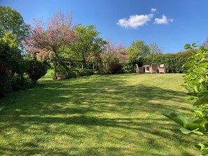 A well-maintained lawn with a wooden fence, outdoor furniture, and flowering trees. - Caldarvan - sleeps 8 guests  in 4 bedrooms (Wadebridge)