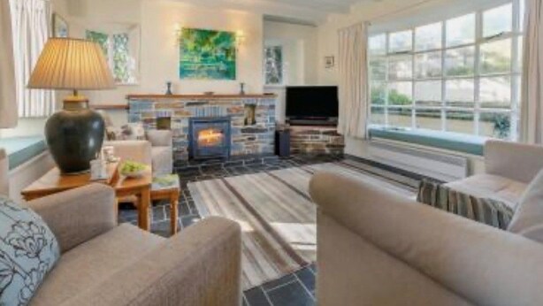 A modern living room with a fireplace, comfortable seating, and a large window. - Cherry Tree Cottage - sleeps 6 guests  in 3 bedrooms (St Minver)