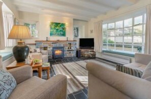 A modern living room with a fireplace, comfortable seating, and a large window. - Cherry Tree Cottage - sleeps 6 guests  in 3 bedrooms (St Minver)