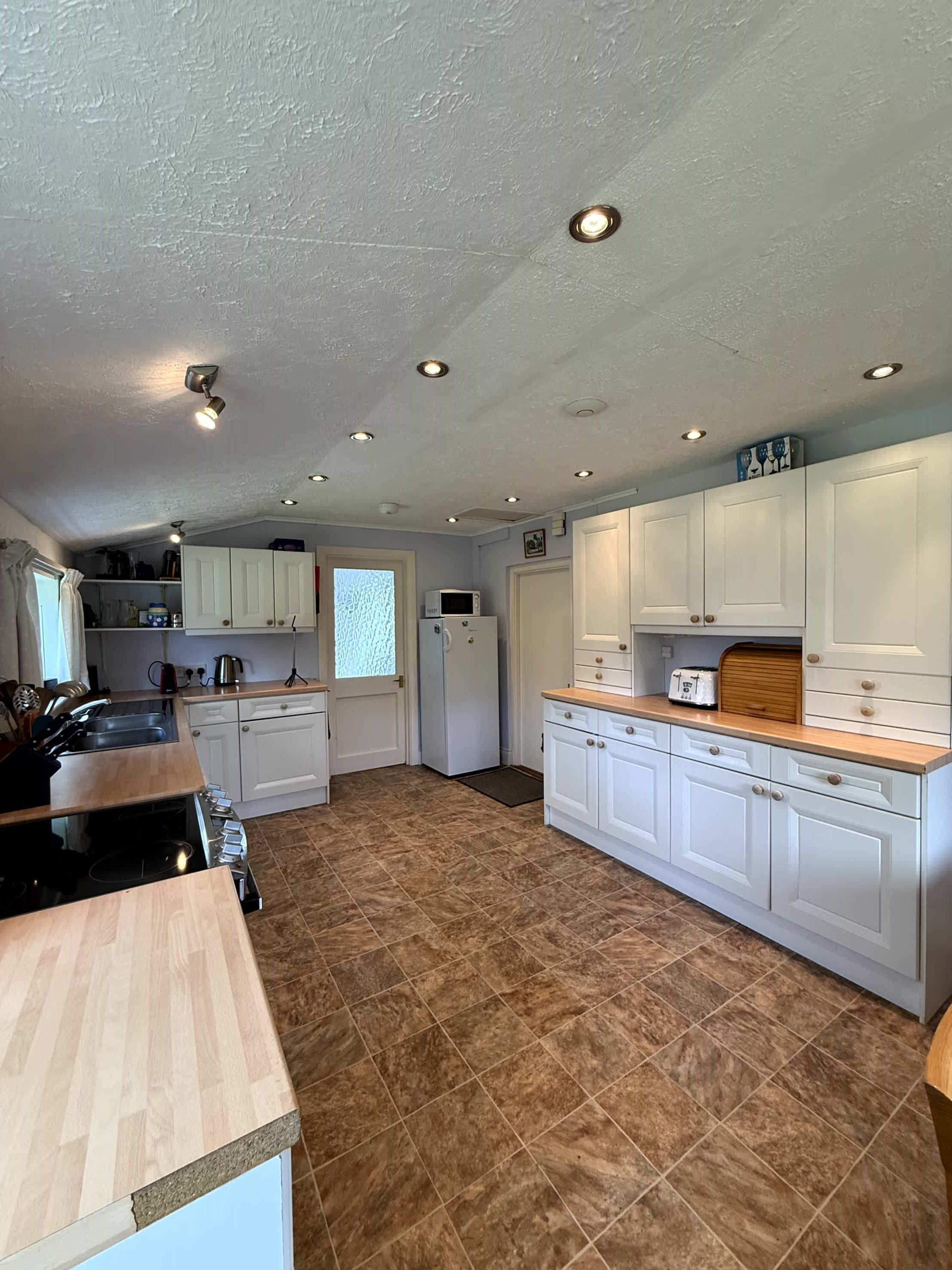A kitchen with white cabinets, a wooden countertop, and a tiled floor.
