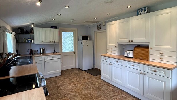 A kitchen with white cabinets, a wooden countertop, and a tiled floor. - Broad Park-Sleeps 11 in 6 Bedrooms (Rock)