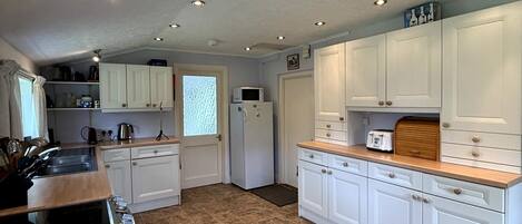 A kitchen with white cabinets, a wooden countertop, and a tiled floor.
