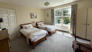 A room with two single beds, a wooden dresser, a chair, and a window with curtains. - Broad Park-Sleeps 11 in 6 Bedrooms (Rock)