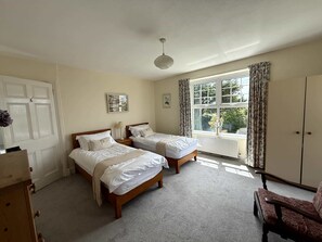 A room with two single beds, a wooden dresser, a chair, and a window with curtains. - Broad Park-Sleeps 11 in 6 Bedrooms (Rock)