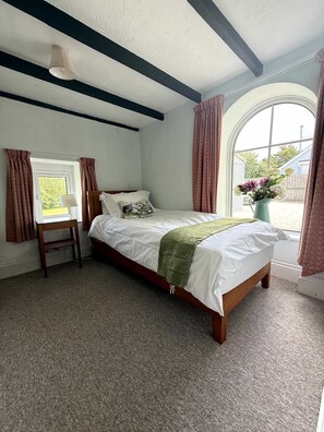 A bedroom with a single bed, a bedside table, a lamp, a window with curtains, and a view of the outside. - Broad Park-Sleeps 11 in 6 Bedrooms (Rock)