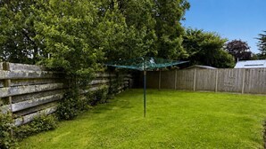A fenced backyard with a grassy lawn and a clothesline. - Broad Park-Sleeps 11 in 6 Bedrooms (Rock)