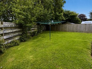 A fenced backyard with a grassy lawn and a clothesline. - Broad Park-Sleeps 11 in 6 Bedrooms (Rock)