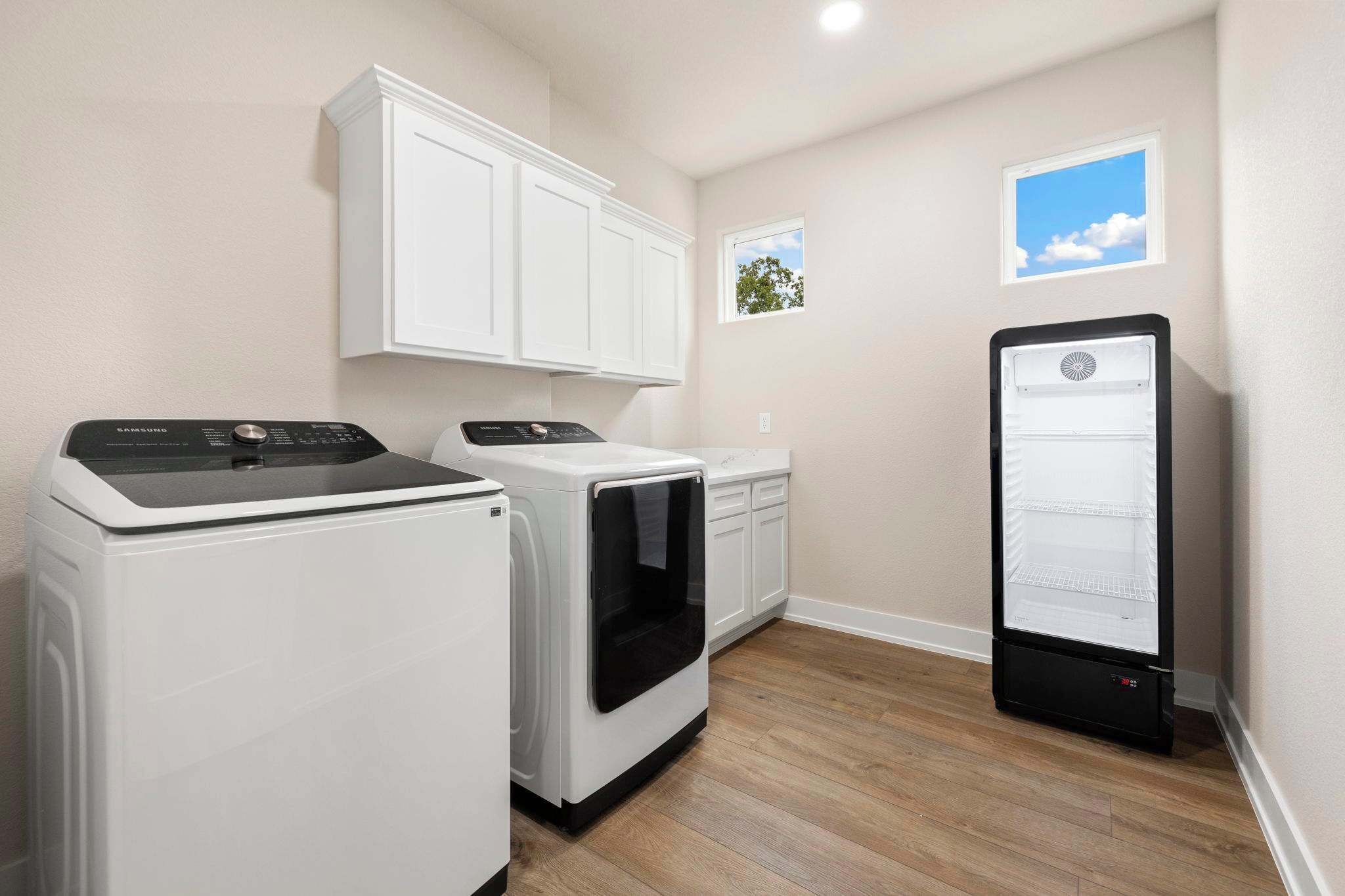 A laundry room with a washing machine, dryer, and a refrigerator.