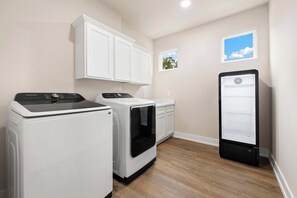 A laundry room with a washing machine, dryer, and a refrigerator.