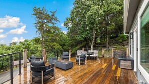 Terraza exterior con suelo de madera, mobiliario para exteriores y una chimenea.