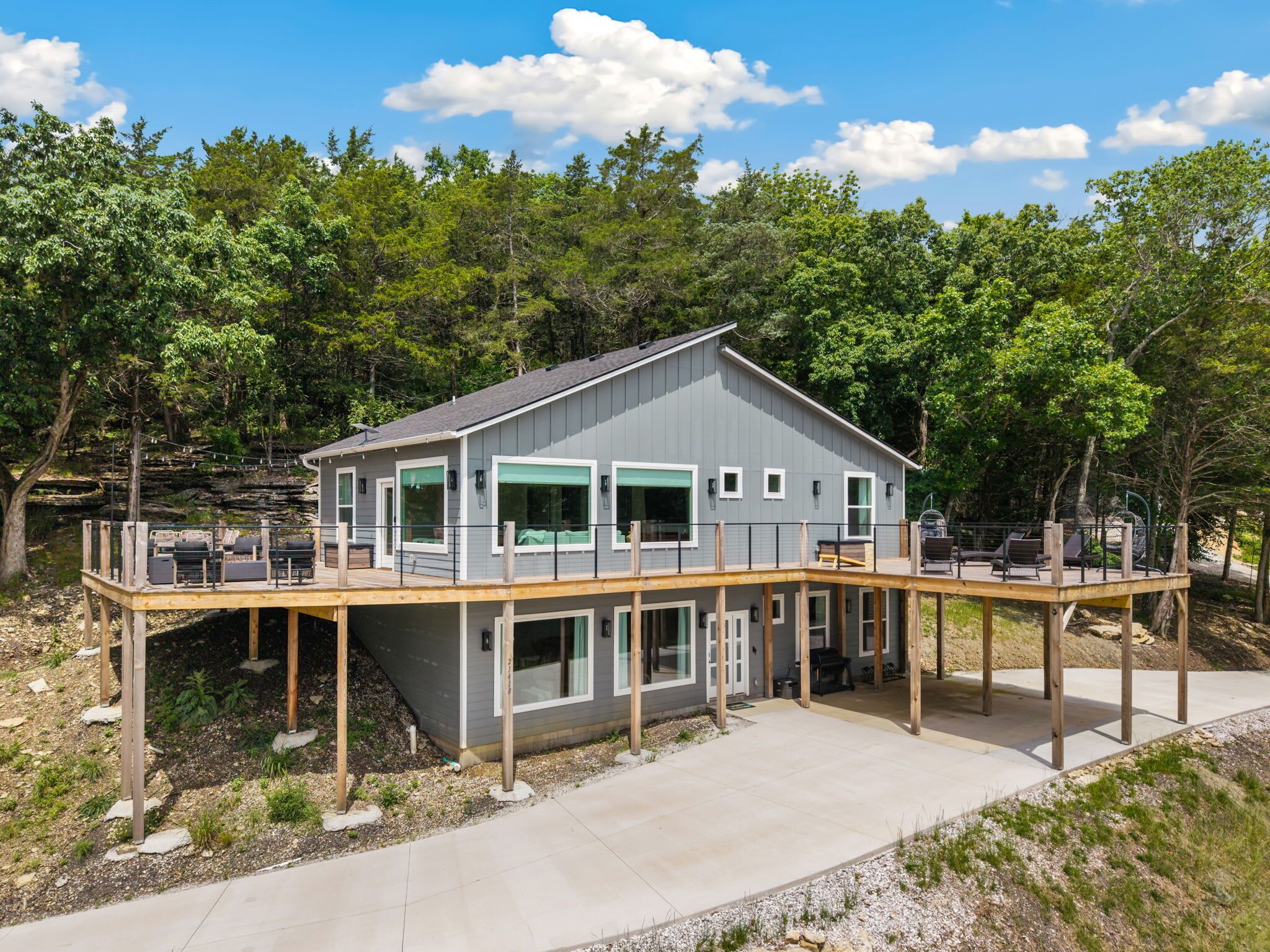 A two-story house with a deck, surrounded by trees.