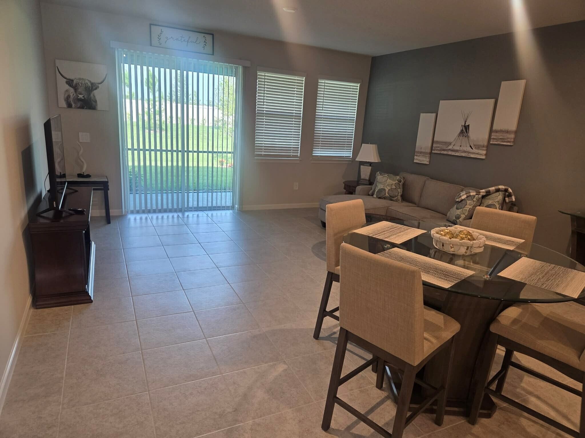 A spacious living area with a dining table, sofa, and a view of a balcony.