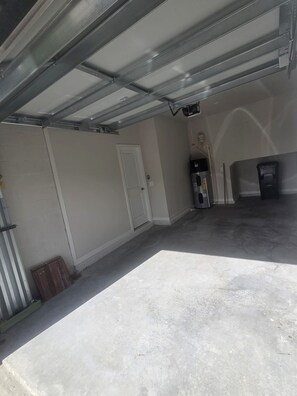 A garage with a concrete floor, a white door, and a water heater. - Peaceful 3-bedroom townhome with AC in charming Parrish (Parrish)