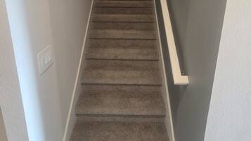 A carpeted staircase with a handrail, leading to a landing with a circular wall decoration.