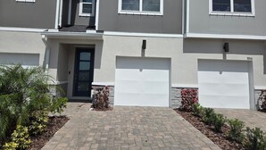 Un immeuble résidentiel à deux étages, doté d’un garage, d’une porte d’entrée et d’une allée pavée.