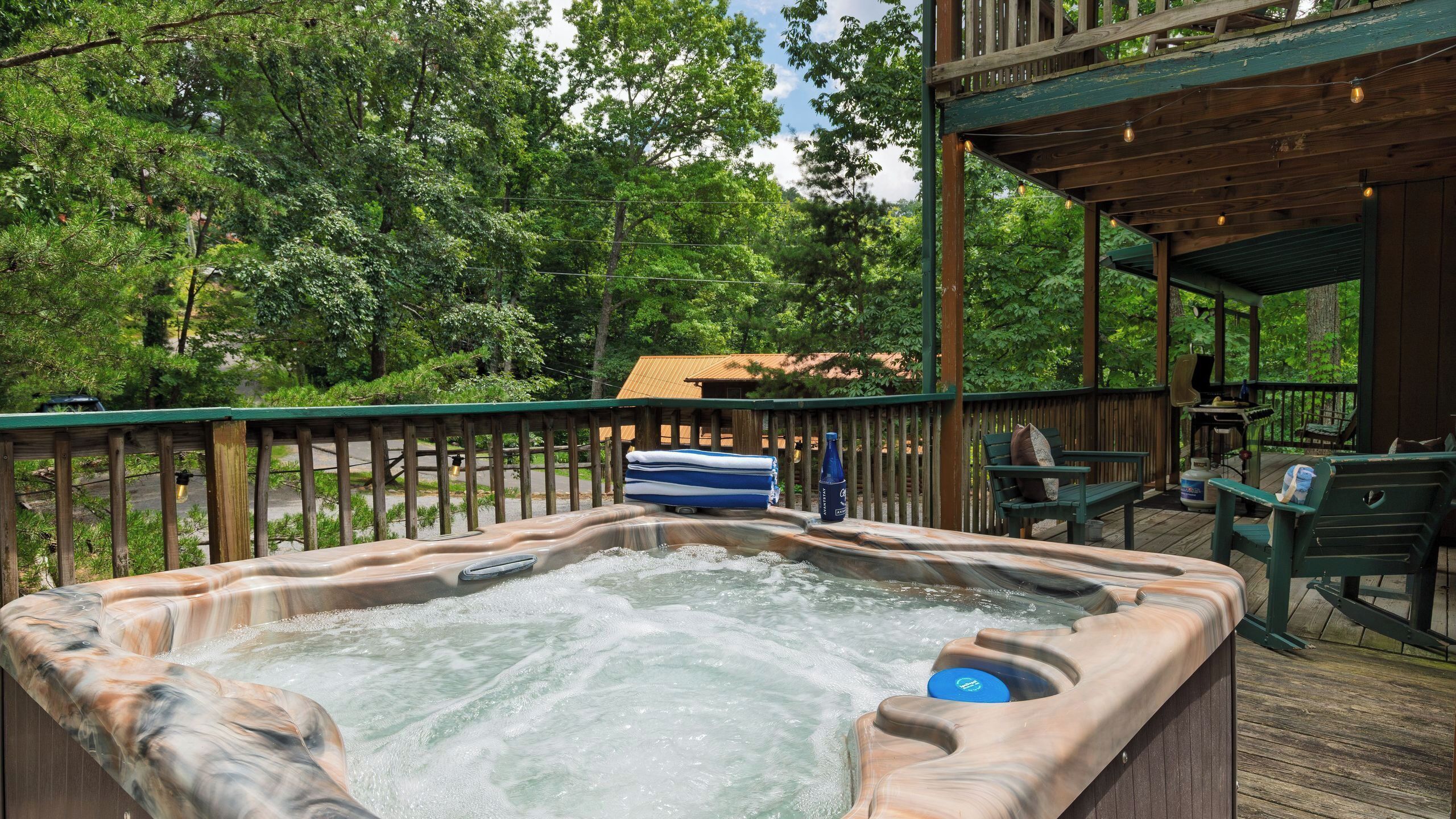 Un jacuzzi en una terraza de madera con vistas a un bosque.