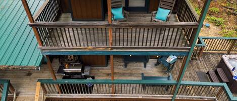 A multi-level wooden deck with outdoor seating and a grill area.